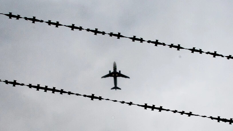 ARCHIV - Ein Flugzeug ist hinter Stacheldraht zu sehen. Foto: Julian Stratenschulte/dpa