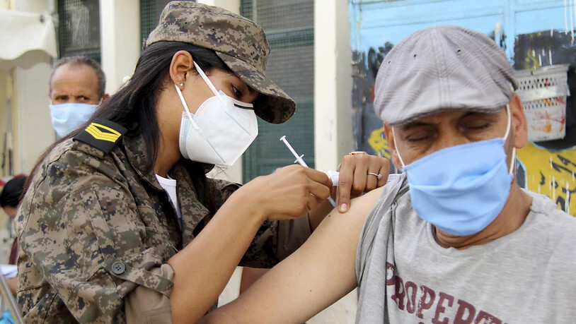 Eine Soldatin verabreicht einem Mann in der Assad-Iben-El-Fourat-Schule den Corona-Impfstoff Vaxzevria während einer Impfaktion. Um die katastrophale Corona-Lage in Tunesien in den Griff zu bekommen, hat eine Impfaktion für bis zu eine Million Bürger im…