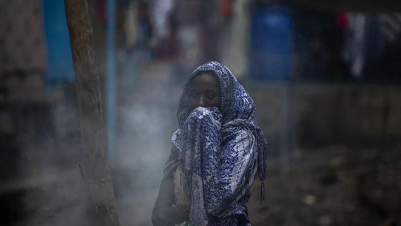 ARCHIV - Eine Frau schützt ihr Gesicht vor Rauch, während sie in einer Schule ein Fladenbrot zubereitet. Der andauernde Konflikt in der Region Tigray hat bereits Hunderttausende Menschen in die Flucht getrieben und große Zerstörung angerichtet. Foto: Ben…