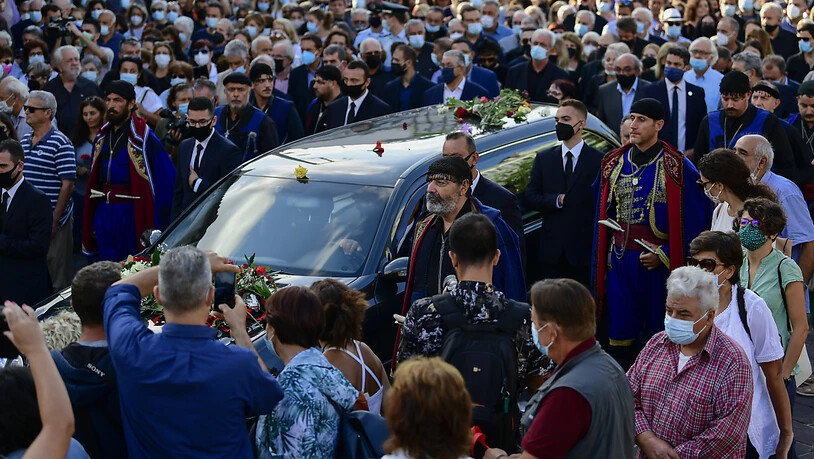 Menschen eskortieren einen Leichenwagen vor der Beerdigung des verstorbenen griechischen Komponisten Mikis Theodorakis. Theodorakis starb am 2. September 2021 im Alter von 96 Jahren. An diesem Donnerstag haben Tausende Kreter von dem Komponisten Abschied…