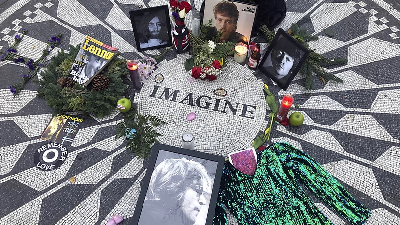 ARCHIV - Fotos, Blumen und Kerzen stehen auf der Gedenkstätte Strawberry Fields im Central Park zur Erinnerung an John Lennon. Vor 50 Jahren veröffentlichte John Lennon seinen Song «Imagine». Das Lied gilt bis heute als hoffnungsvolle Hymne für den…