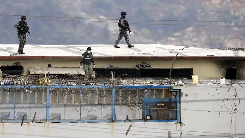 dpatopbilder - Polizisten laufen über das Dach eines Gefängnisses, nachdem dort Unruhen ausbrachen. Bei erneuten gewalttätigen Auseinandersetzungen in einem Gefängnis in Ecuador sind Medien zufolge mindestens 58 Häftlinge ums Leben gekommen. (zu dpa: …