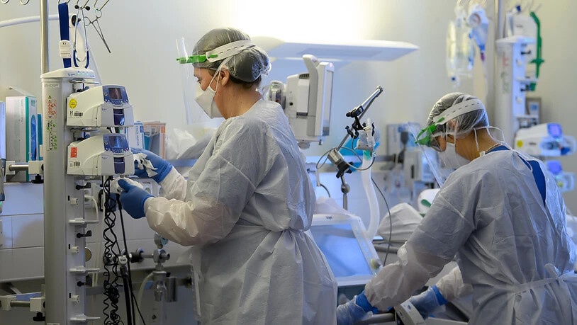 ARCHIV - SYMBOLBILD Intensivpflegerinnen sind in Schutzkleidungen auf der Covid-19-Intensivstation einer Klinik mit der Versorgung von Corona-Patienten beschäftigt. Foto: Robert Michael/dpa-Zentralbild/dpa