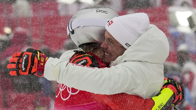 Teamkollege Gino Caviezel, der selber starker Siebter wurde, umarmt Olympiasieger Marco Odermatt