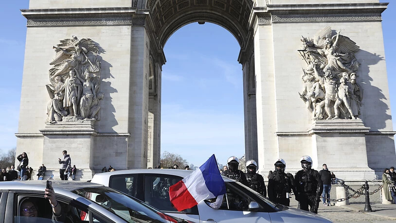 Demonstranten in einem Konvoi fahren am Arc de Triomphe auf der Avenue des Champs-Elysees vorbei. Foto: Adrienne Surprenant/AP/dpa