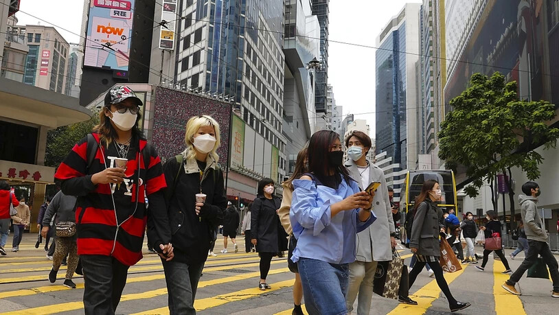 Menschen mit Masken gehen durch eine Straße in einem Hongkonger Einkaufsviertel. Foto: Vincent Yu/AP/dpa