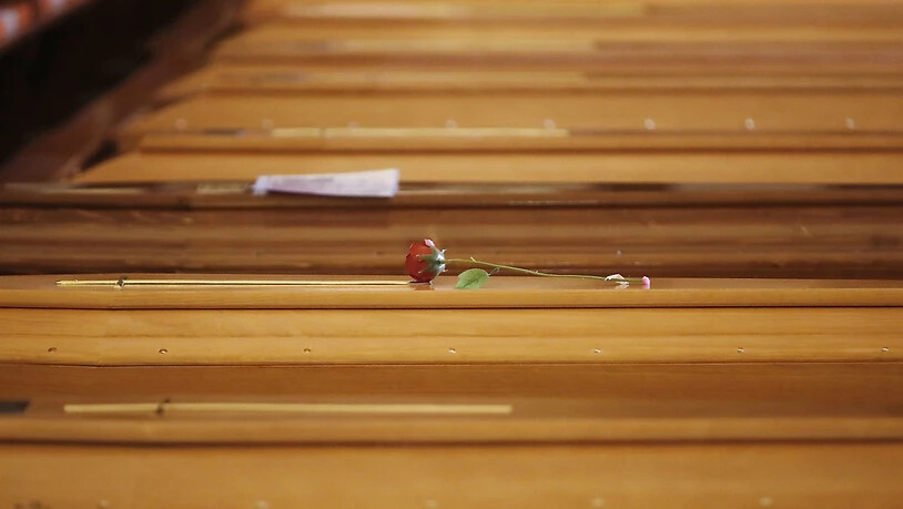 ARCHIV - Eine rote Plastikrose liegt in der Kirche San Giuseppe auf einem der aufgereihten Särge in Seriate, einer Gemeinde in der italienischen Provinz Bergamo, während der dramatischen Lage Italiens in der Coronavirus-Krise. Foto: Antonio Calanni/AP/dpa