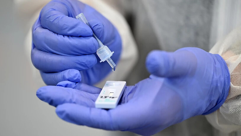 ARCHIV - Ein Helfer verarbeitet eine Probe für einen Corona-Schnelltest. Österreich setzt die kostenlosen Corona-Tests fort. Ab 1. April würde jedoch die Zahl der kostenlosen PCR-Tests und Antigen-Tests auf jeweils fünf pro Bürger im Monat beschränkt,…