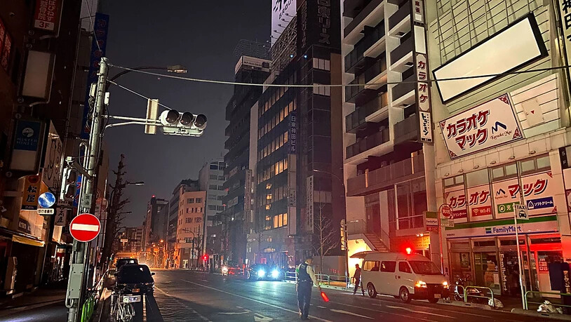 Ein Polizist steht während eines Stromausfalls in der Hauptstadt auf der Straße und leitet den Verkehr. Foto: -/Kyodo News/AP/dpa - ACHTUNG: Nur zur redaktionellen Verwendung und nur mit vollständiger Nennung des vorstehenden Credits