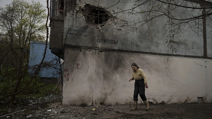 Eine Frau geht nach einem russischen Angriff an einem beschädigten Gebäude in Charkiw vorbei. Foto: Felipe Dana/AP/dpa