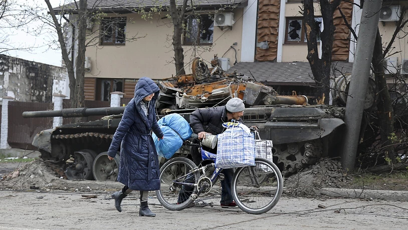 dpatopbilder - Zivilisten gehen an einem Panzer vorbei, der bei schweren Kämpfen in einem von den von Russland unterstützten Separatisten kontrollierten Gebiet in Mariupol zerstört wurde. Foto: Alexei Alexandrov/AP/dpa