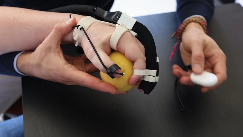 Ein Patient mit gelähmter Hand trainiert seine Greiffähigkeit mit dem Exoskelett.