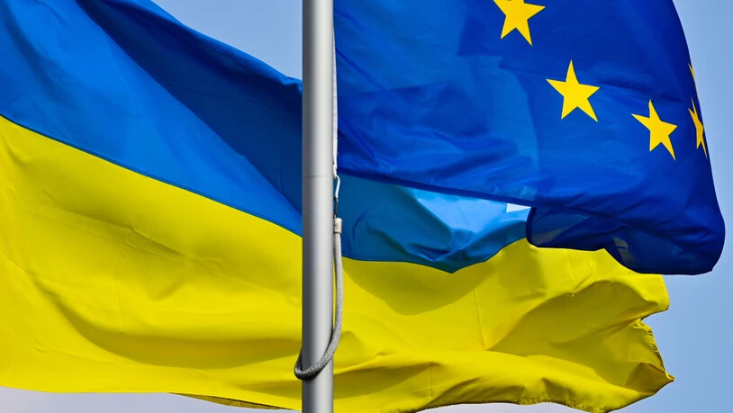 ARCHIV - Die Fahnen der Ukraine und der EU wehen im Wind. Kiew hatte kurz nach Beginn des russischen Kriegs gegen die Ukraine den Beitritt zur EU beantragt. Die EU-Kommission will nun eine Empfehlung abgeben, ob dem Land der Kandidatenstatus gewährt…
