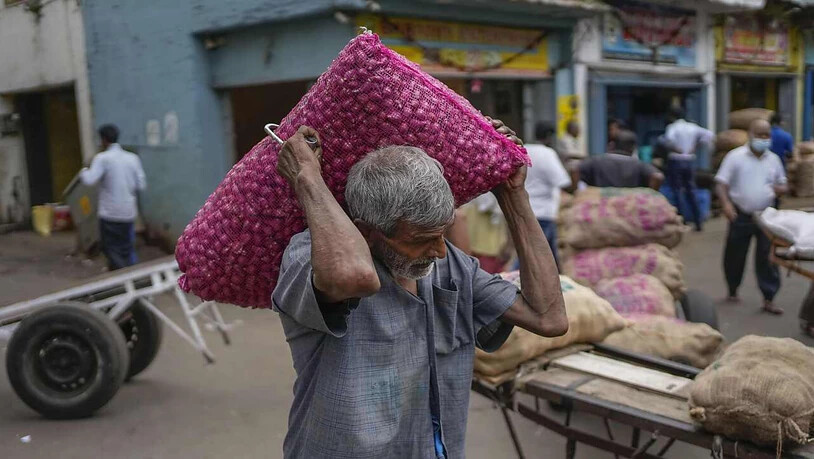 Ein Mann trägt einen Sack mit importierten Zwiebeln auf einem Markt in Colombo. Foto: Eranga Jayawardena/AP/dpa