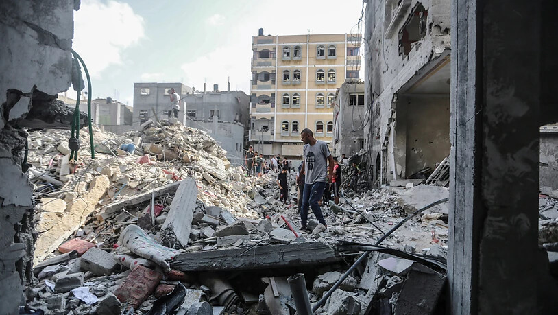 Palästinenser inspizieren die Trümmer eines Gebäudes, an dem der südliche Kommandeur des Islamischen Dschihads, Chalid Mansur, bei einem Luftangriff ums Leben gekommen ist. Foto: Mohammed Talatene/dpa