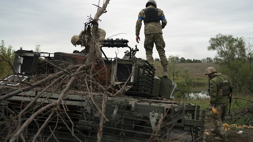 Ukrainische Soldaten stehen auf einem zerstörten russischen Panzer in einem zurückeroberten Gebiet nahe der Grenze zu Russland in der Region Charkiw. Foto: Leo Correa/AP/dpa