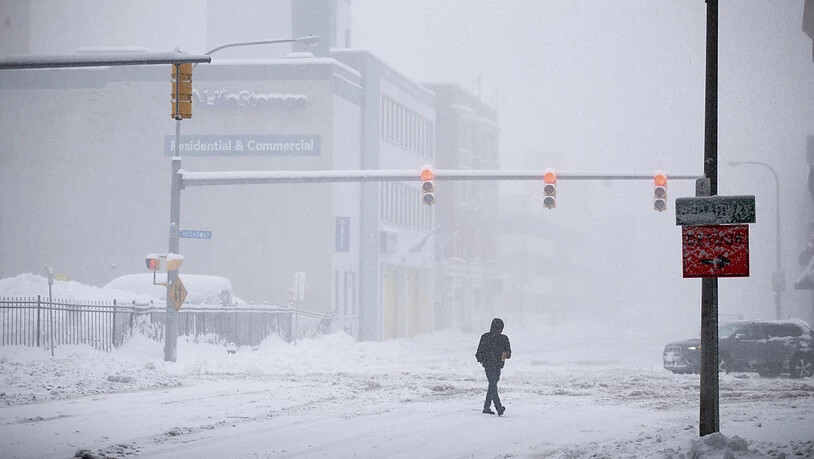 Eine Person überquert die Ellicott Street bei Schneefall. Ein gefährlicher Schneesturm hat Teile des westlichen und nördlichen New Yorks lahmgelegt, wobei mancherorts bisher schon fast 60 cm Schnee liegt. Foto: Joshua Bessex/FR171816 AP/dpa