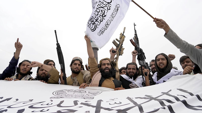 ARCHIV - Taliban-Kämpfer versammeln sich mit Fahnen, einem Banner und Gewehren. Foto: Ebrahim Noroozi/AP/dpa