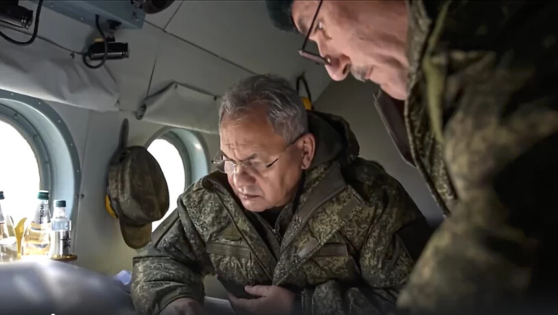 HANDOUT - Auf diesem vom Pressedienst des russischen Verteidigungsministeriums veröffentlichten Handout-Foto sieht sich Sergej Schoigu (l), Verteidigungsminister von Russland, an Bord eines Militärhubschraubers an einem ungenannten Ort in der Ukraine…