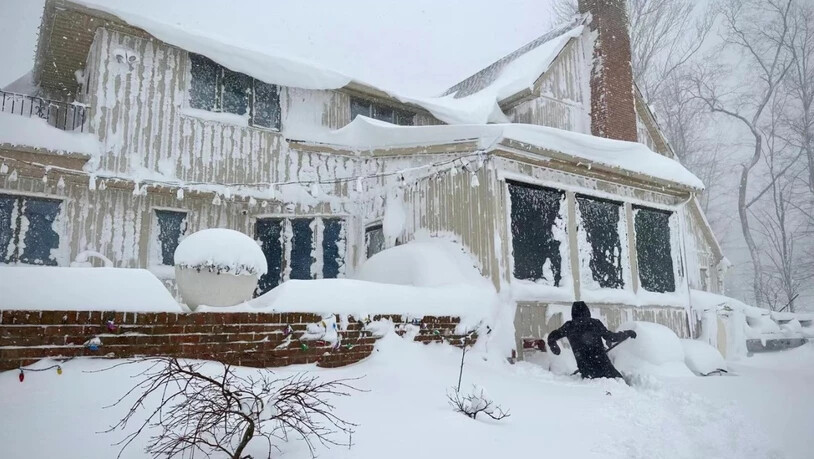 Ein Anwohner entfernt Schnee von einem Gebäude in Amherst im US-Bundesstaat New York. Foto: -/XinHua/dpa