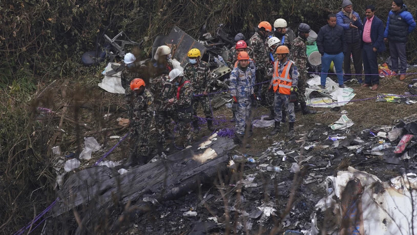 Rettungskräfte durchsuchen die Absturzstelle im Wrack eines Passagierflugzeugs. Foto: Yunish Gurung/AP/dpa