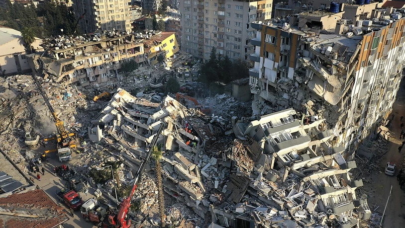 Rettungsteams suchen nach Menschen, während Kräne Trümmer von zerstörten Gebäuden entfernen. Foto: Hussein Malla/AP/dpa