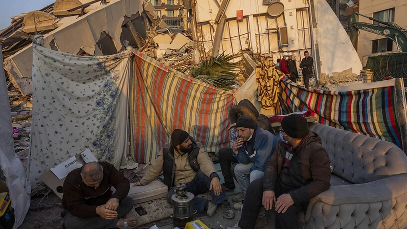 dpatopbilder - Männer sitzen vor den Trümmern bei dem Erdbeben zerstörter Gebäude. Die Zahl der Menschen, die in der Türkei durch das Erdbeben getötet worden sind, ist auf 41 020 gestiegen. Foto: Bernat Armangue/AP/dpa