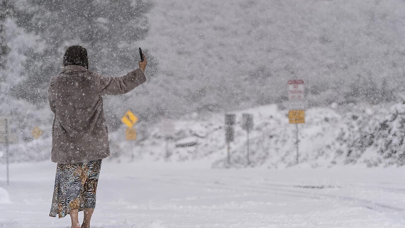 dpatopbilder - Eine Frau steht auf einer schneebedeckten Straße und macht ein Selfie im Angeles National Forest in der Nähe von La Canada Flintridge. Foto: Jae C. Hong/AP/dpa