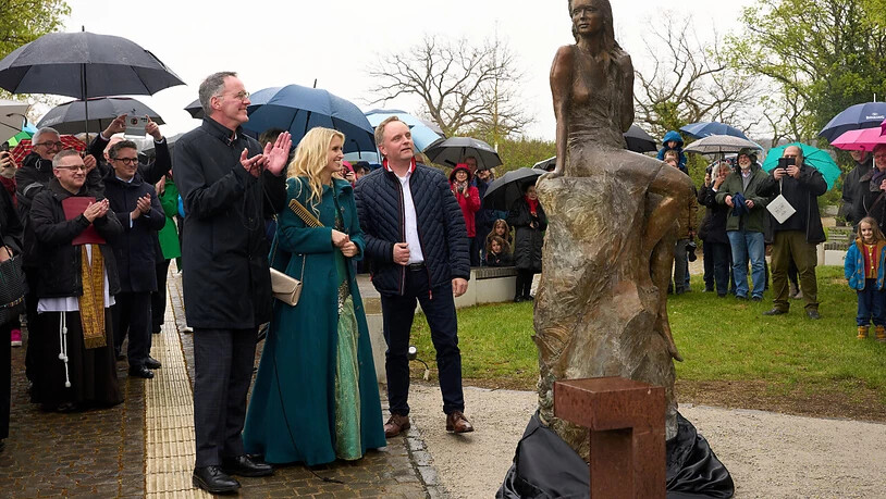 Michael Ebling (SPD, l), rheinland-pfälzischer Innenminister, Loreley Katharina Blanckart und Verbandsbürgermeister Mike Weiland enthüllen die neu gestaltete Loreley-Statue auf dem Loreley-Plateau hoch über dem Rhein. Foto: Thomas Frey/dpa
