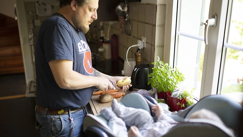 Ein Vater breitet an seinem freien Tag zu Hause Brei für seine sechs Monate alte Tochter zu. (Symbolbild)