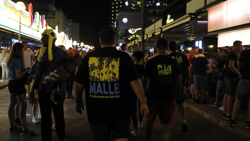 ARCHIV - Männer, die ein T-Shirt mit der Aufschrift «Malle» tragen, gehen durch die Schinkenstraße im so genannten Ballermann-Viertel auf Mallorca. Foto: Clara Margais/dpa