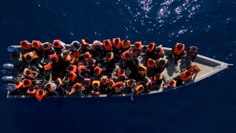 ARCHIV - Aus Eritrea, Libyen und dem Sudan geflüchtete Menschen sitzen in einem Holzboot im Mittelmeer, etwa 30 Meilen nördlich von Libyen. Foto: Joan Mateu Parra/AP/dpa