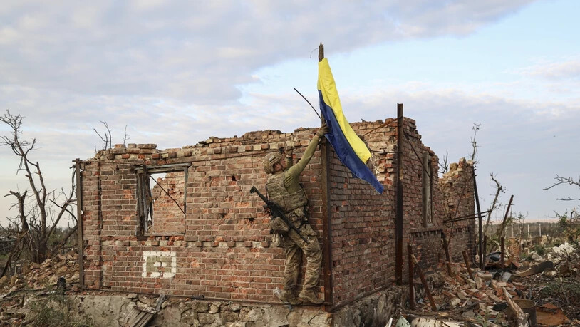 Ein ukrainischer Kommandeur hisst die Nationalflagge als Symbol der Befreiung des Frontdorfes Andrijewka in der Region Donezk. Foto: Alex Babenko/AP/dpa