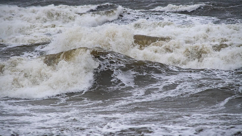 Wellen schlagen an den Ostseestrand. Wegen eines Sturmtiefs sind an der Ostseeküste die ersten Straßen und Uferbereiche vom Hochwasser überschwemmt worden. So standen am Morgen sowohl in Wismar als auch in Kiel und und Flensburg zahlreiche Straßen und…