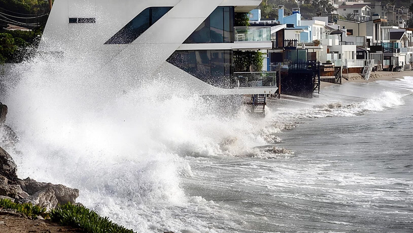 Wellen schlagen gegen ein Haus an der kalifornischen Küste in Malibu Beach.