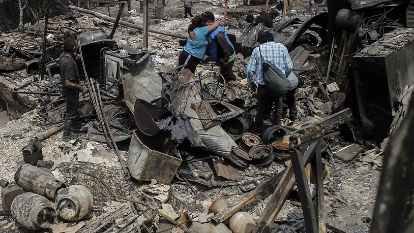 dpatopbilder - Einheimische umarmen sich inmitten von Trümmern und ausgebrannten Häusern, nachdem die Waldbrände ihre Nachbarschaft in Vina del Mar zerstört haben. Foto: Cristobal Basaure/AP