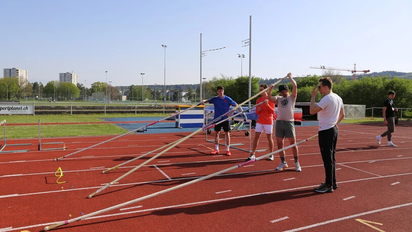Einblick in die Leichtathletik: Die Teilnehmenden (hier drei junge Männer) bekommen unter den Augen von Adrian Kübler (rechts) die Möglichkeit, sich im Stabhochsprung zu versuchen.