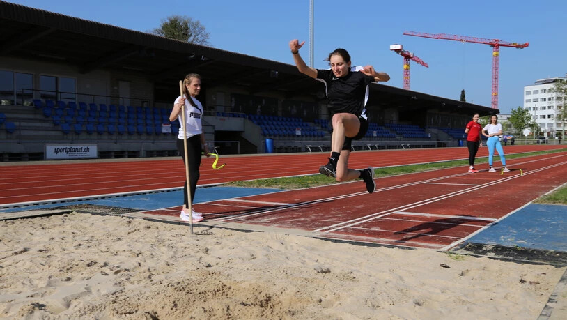 Einblick in die Leichtathletik: Die Teilnehmenden (hier eine junge Frau) bekommen unter den Augen von Annik Kälin (links) die Möglichkeit, sich im Weitsprung zu versuchen.