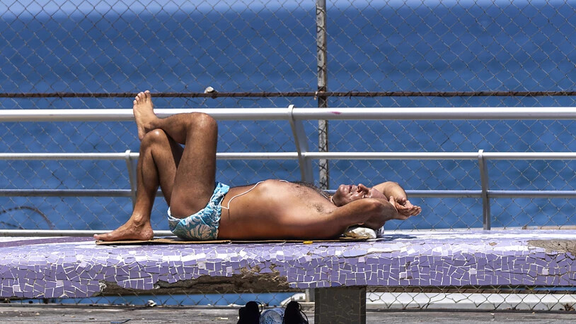 Ein Mann liegt auf der Strandpromenade von Beirut und sonnt sich. Foto: Hassan Ammar/AP/dpa