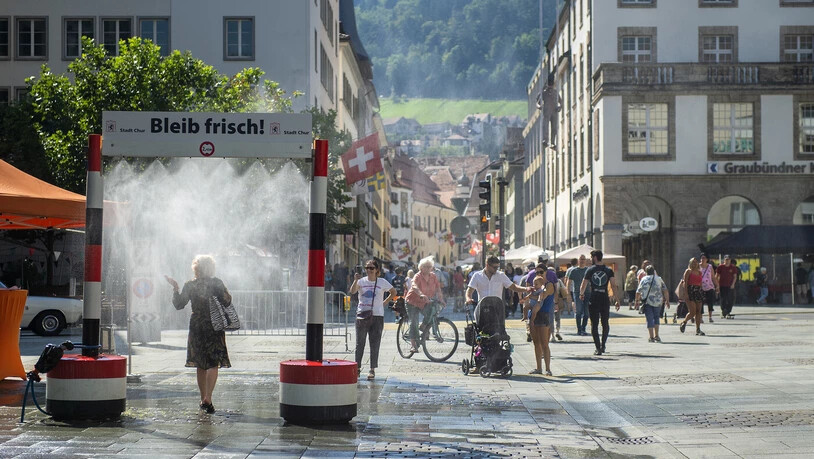 Abkühlung mitten in Chur: Passanten kühlen sich mit einer Regendusche ab.
