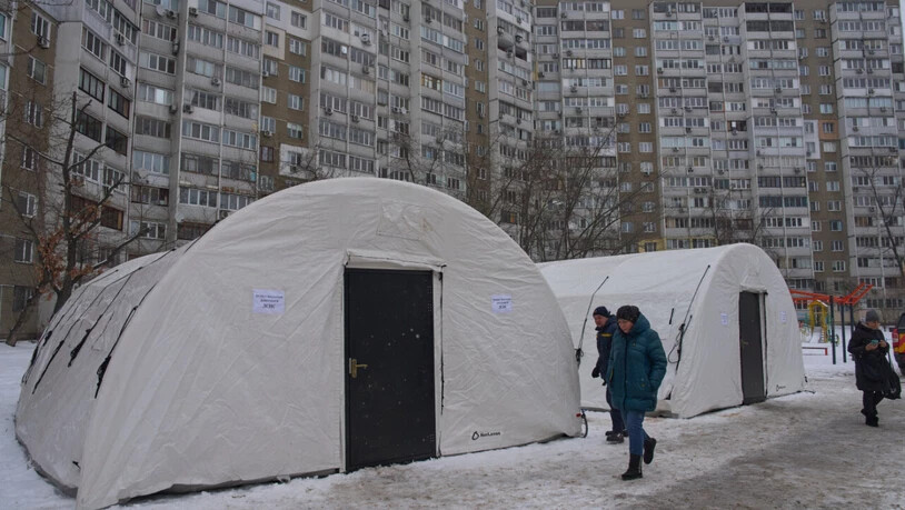 Anwohner gehen an einem der Zelte in Kiew vorbei, die der Katastrophenschutz nach den russischen Luftangriffen auf den ukrainischen Energiesektor aufgestellt hat. Foto: Efrem Lukatsky/AP/dpa/Archivbild