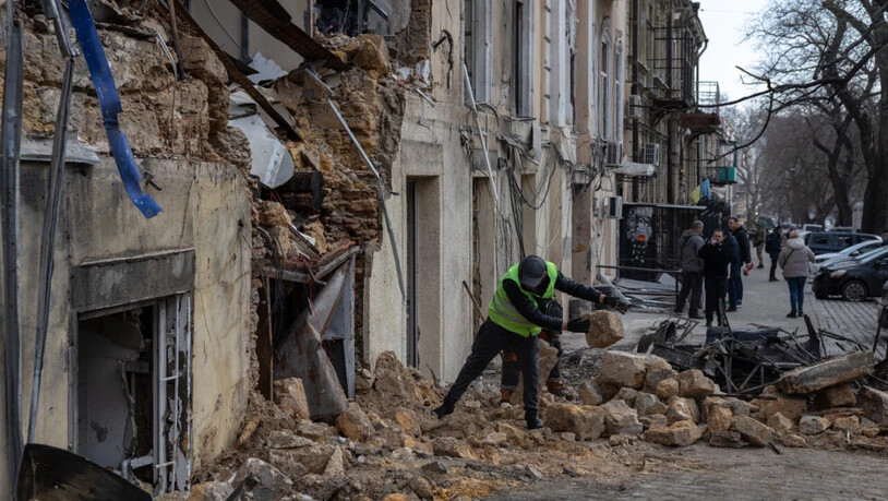 ARCHIV - Ein städtischer Arbeiter räumt die Trümmer eines Wohnhauses auf, das nach einem russischen Drohnenangriff beschädigt wurde. Foto: Oleg Grekov/AP/dpa