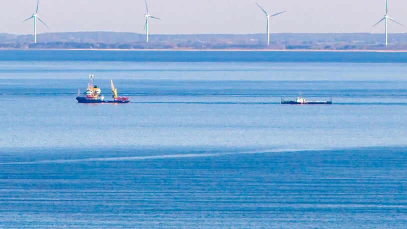 dpatopbilder - Ein Schiff zieht vor Fehmarn die Barge mit dem gestrandetem Wal. Im Hintergrund ist die dänische Küste zu sehen. Foto: Bodo Marks/dpa