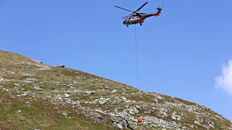 Ein Helikopter transportiert einen Stein zum Auslösepunkt.  