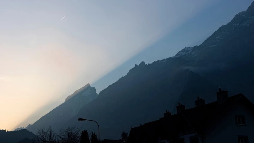 Das Sonnenlicht fällt auf die Bergflanke beim Mättlistock.