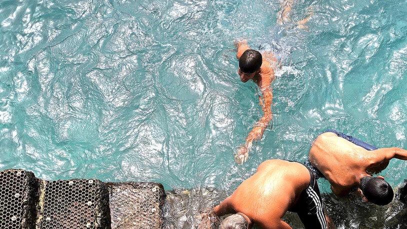 Nur noch bedingt eine Abkühlung: Drei Männer steigen am Strand von Guimar auf der spanischen Touristeninsel Teneriffa aus dem Wasser.  