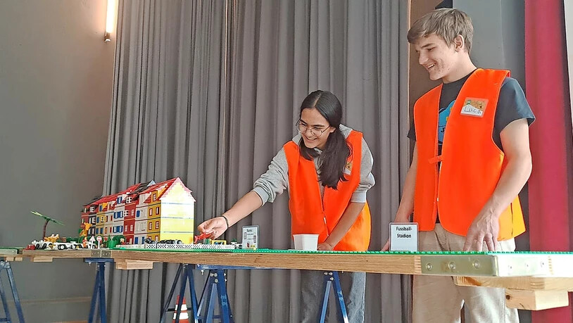 Zwei Leitpersonen begutachten die im Entstehen begriffene Stadt.