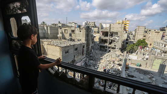 Ein palästinensisches Kind blickt aus einem Fenster auf die Trümmer eines Gebäudes, an dem der südliche Kommandeur des Islamischen Dschihads, Chalid Mansur, bei einem Luftangriff ums Leben gekommen ist. Foto: Mohammed Talatene/dpa