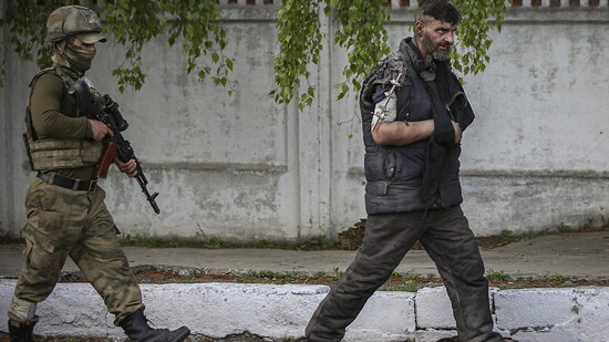 Ein russischer oder pro-russisch-separatistischer Soldat (links) führt einen Kämpfer des ukrainischen Asow-Regiments aus dem Stahlwerk in Mariupol ab. (Aufnahme vom 17. Mai 2022)