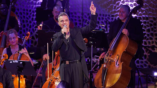 Anlässlich des 25. Jubiläums seiner Solo-Karriere gab Robbie Williams, britischer Sänger und Songwriter, zusammen mit dem Orchester der Neuen Philharmonie Frankfurt in der Elbphilharmonie ein mitreißendes Konzert. Foto: Georg Wendt/dpa - ACHTUNG: Nur zur…